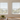 Recess-fit and face-fit white Venetian blinds with standard cords installed on two living room windows. 